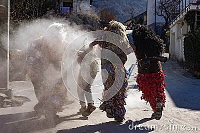 Slovene traditional carnival masks `Ta grdi` running after the teenager and throwing the ash at him Editorial Stock Photo