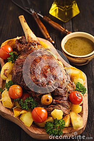 Slow baked lamb leg with potatoes and sauce. Stock Photo