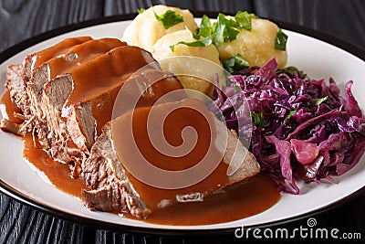 Slow Cooker Pot Roast Sauerbraten with spicy sauce, potato dumplings and red cabbage close-up. horizontal Stock Photo