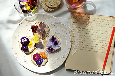 Slow living conceptual photography with edible flowers snacks and diary on a white table Stock Photo