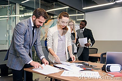 Slow motion of handsome enterprising bearded businessman standing near boardroom table with his attentive female Stock Photo