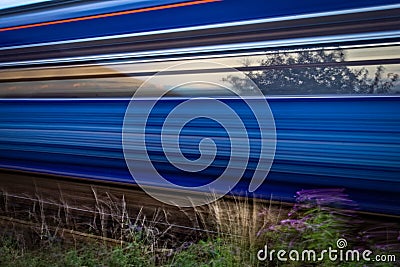 Slow shutter shot of blue and red train speeding past Stock Photo