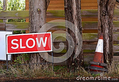 SLOW traffic sign with broken orange and white traffic cones Stock Photo