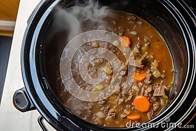 slowcooker with beef stew simmering, top view steam visible Stock Photo