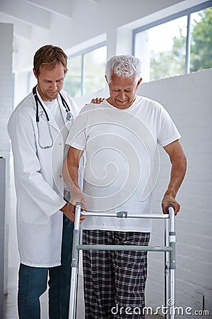 Slowly getting there. a male doctor assisting his senior patient whos using a walker for support. Stock Photo