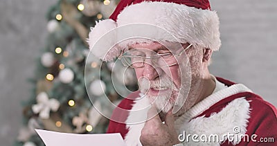 Sluiting van de leesbrief van de kerstman en een onhandig gezicht Senior man met een witte baard die denkt dat hij een cadeau hee stock video Sluiting van de leesbrief van de kerstman en een onhandig gezicht Senior man met een witte baard die denkt dat hij een cadeau hee stock video