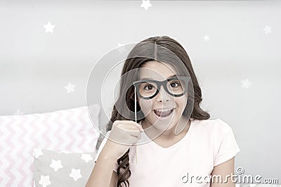 Slumber party photo booth props. Kid girl cheerful posing with vintage black eyeglasses party attribute. Prepare photo Stock Photo