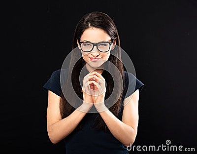 Sly concentrated happy business woman in glasses looking in camera and plotting new earring solution and fingering on black Stock Photo