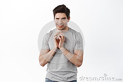 Sly young man scheming, steeple fingers and smiling devious, evil plan, standing over white background Stock Photo