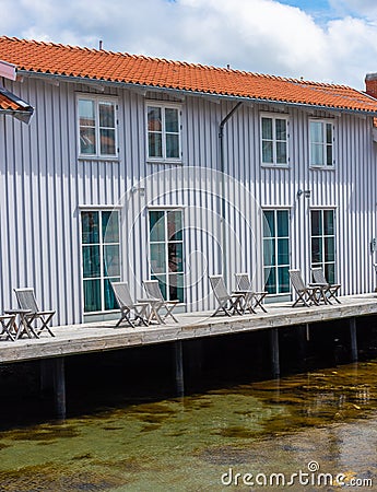 Small apartment building by the sea. Wooden chairs and tables on the deck by the water Stock Photo