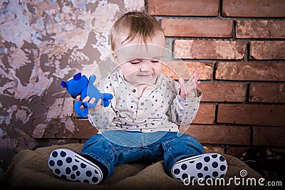 Small baby boy is confused and does not understand what is happening here. He is sitting on a iron barrel. Infant child on the Stock Photo