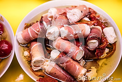 Small bacon starter rolls with fresh goat cheese for snacking Stock Photo