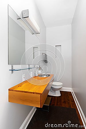 A small bathroom with a floating wood cabinet and stainless steel sink. Stock Photo