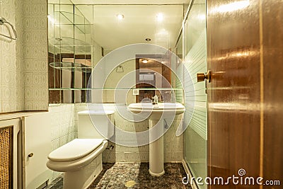 Small bathroom with pedestal porcelain sink, large mirror on the wall and old tiles Stock Photo