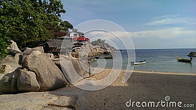 Small beach, big limestones and some Buildings close to the Ocean. Holidays on the Island Koh Tao. Stock Photo