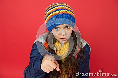 Small beauty red background. little girl puffer jacket and knitted hat. care yourself in cold weather. kid pointing Stock Photo