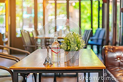 A small bell for calling the waiter and artificial flowers in an aluminum pot and drinking water bottle placed on a table in a Stock Photo