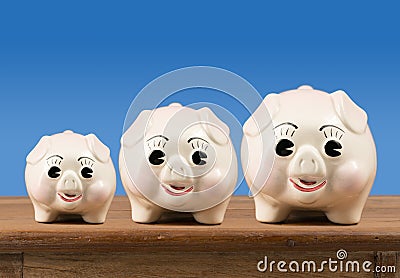 Small medium and large piggy banks on shelf Stock Photo