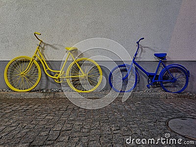 Yellow and blue bike leaned againist the wall Stock Photo