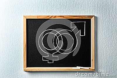 Small blackboard with drawn gender symbols on wall. Sex education Stock Photo