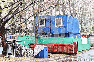 Small blue change house for workers at construcrion area with construction materials around on gloomy day. Stock Photo