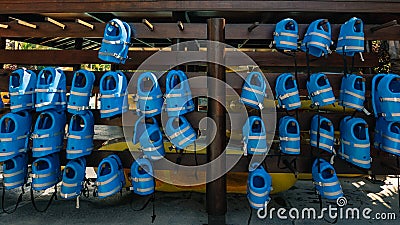 Small blue life jackets for kids are hanging in row at poo Stock Photo