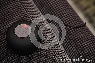 Small bluetooth speaker being charged on the couch close up view Stock Photo