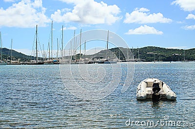 Small boat floating on the ocean, with sailboats and mountains in the background Stock Photo