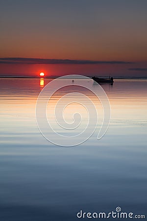 Small boat laying at beach sun rise calm sea Stock Photo