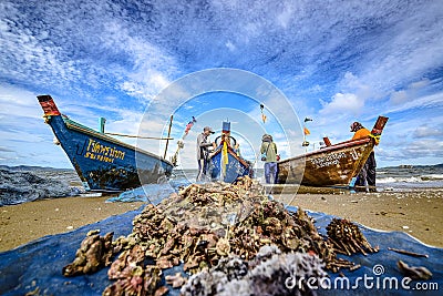 A small boat local fishery group is removing crabs, fish and sea creatures caught from their nets at Jomtien Beach Editorial Stock Photo