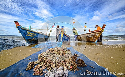 A small boat local fishery group is removing crabs, fish and sea creatures caught from their nets at Jomtien Beach Editorial Stock Photo