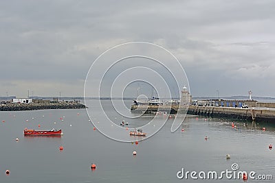 Small boats along a pier with lighthouse in the harbor of Howth Editorial Stock Photo