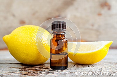 Small bottle of essential lemon oil on the old wooden background. Aromatherapy, spa and herbal medicine ingredients. Stock Photo