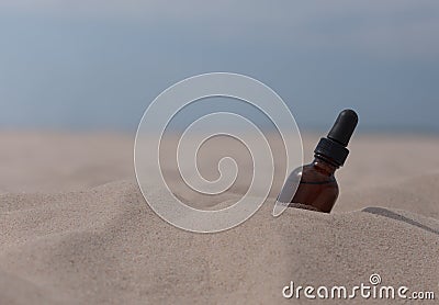 A small bottle of herbal extract covered with sand on the beach Stock Photo