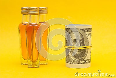 Small bottles with alcohol on a yellow background and money dollars, the proceeds from the sale of alcohol, close-up, photography Stock Photo