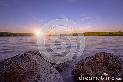 Small boulders submerged in water of a lake on a lakeshore at dusk Stock Photo