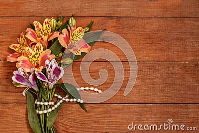 A small bouquet of Alstroemeria with a pearl thread on wooden brown background Stock Photo