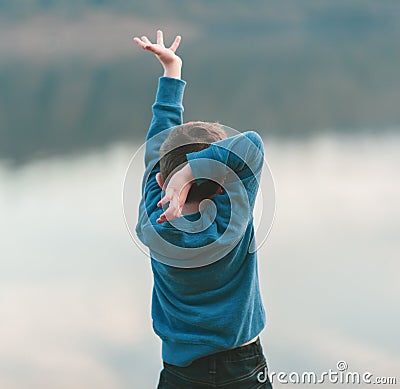 A small boy dances against a river backdrop Stock Photo