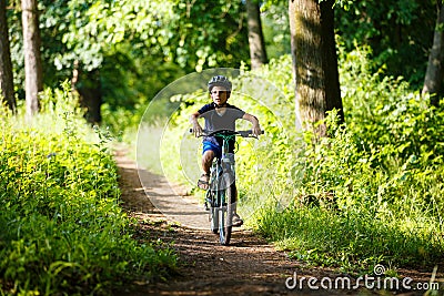 Small boy in helmet riding bicycle in park Stock Photo