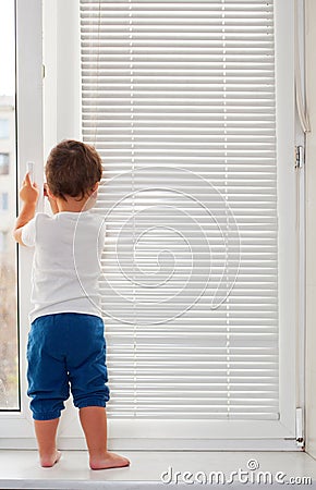 Small boy standing on window-sill Stock Photo