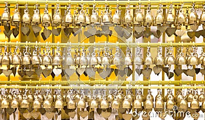 Small brass praying bells big group hanging in steel line patterns at Phra That Hariphunchai temple in Lamphun , Thailand Stock Photo