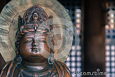 Small bronze Buddha statue with crown on his head in an old Buddhist temple of Kiyomizu Dera in Kyoto, Japan. Arts and symbols of Stock Photo