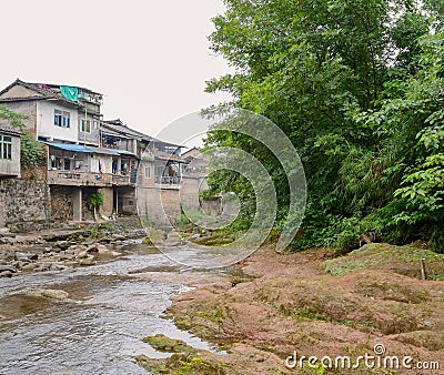 Small brook before aged dwelling buildings in light summer rain Stock Photo