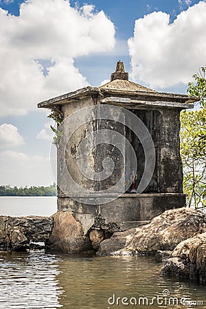 A small Buddhist prayer tower on rocks in the middle of the Bentota Ganga river in the jungle on the island of Sri Lanka Stock Photo