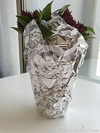 A small bunch of basil in a cup wrapped with tin foil Editorial Stock Photo