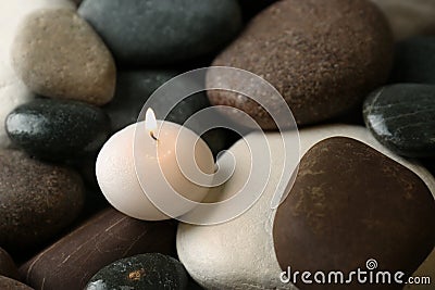 Small burning candle on beautiful spa stones Stock Photo