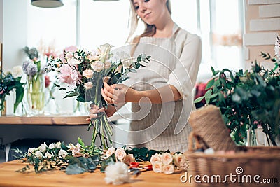 Smiling lovely young woman florist arranging plants in flower shop Stock Photo