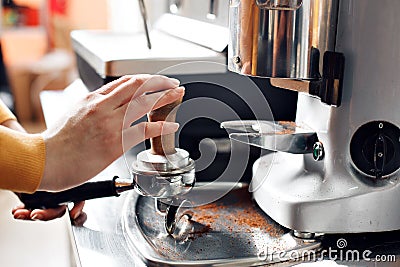 Small business, people and service concept - woman or waiter in apron with holder and tamper preparing coffee at coffee Stock Photo