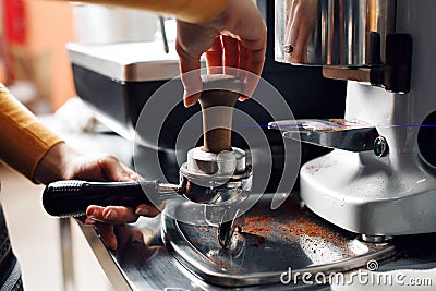 Small business, people and service concept - woman or waiter in apron with holder and tamper preparing coffee at coffee Stock Photo