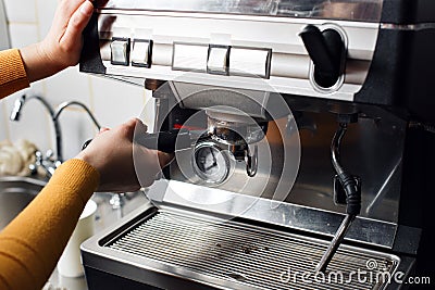 Small business, people and service concept - woman or waiter in apron with holder and tamper preparing coffee at coffee Stock Photo